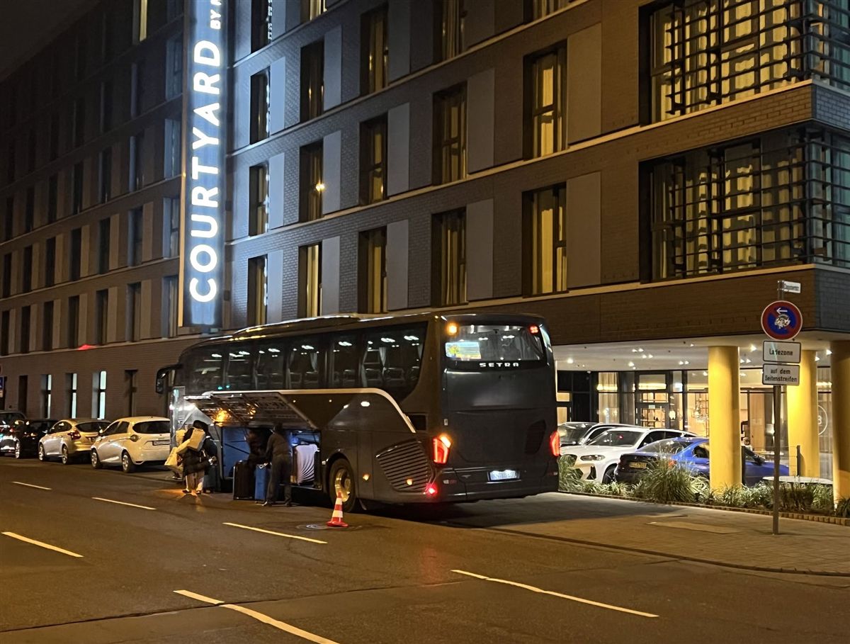Musicians unloading luggage from a coach outside the hotel at night