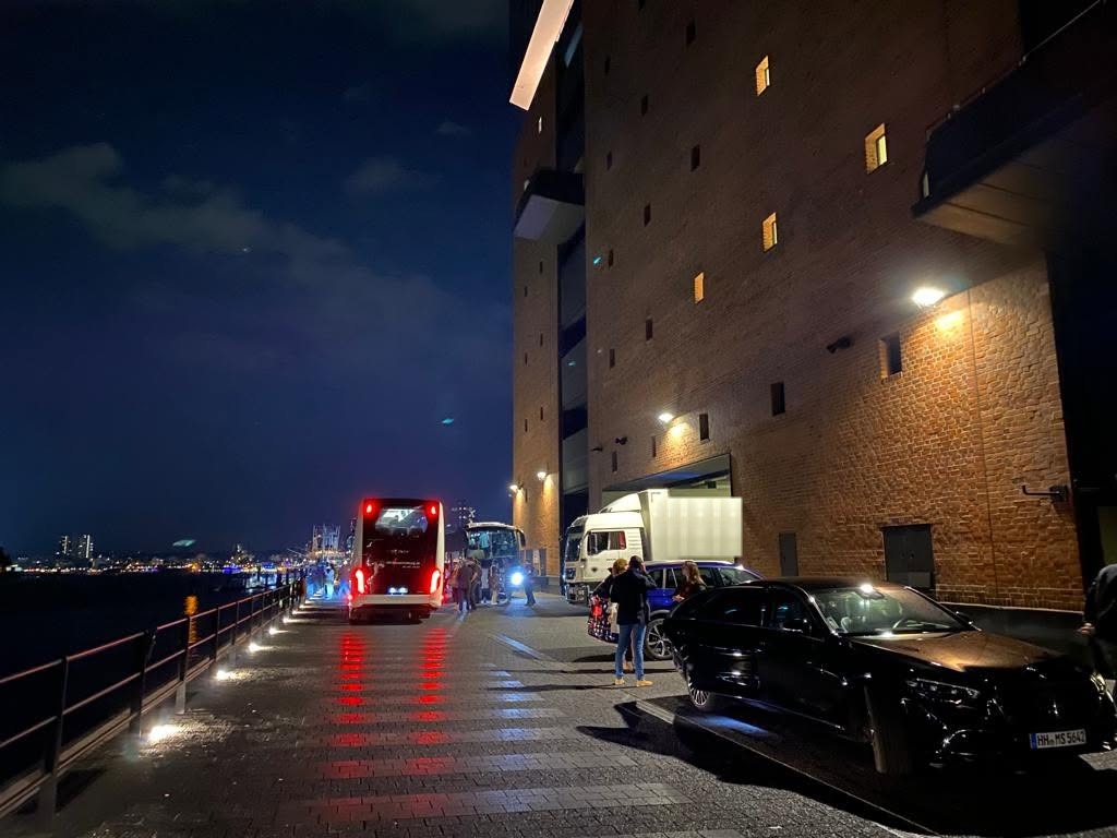 Coaches, tour truck and sedan at the Elbphilharmonie loading zone at night