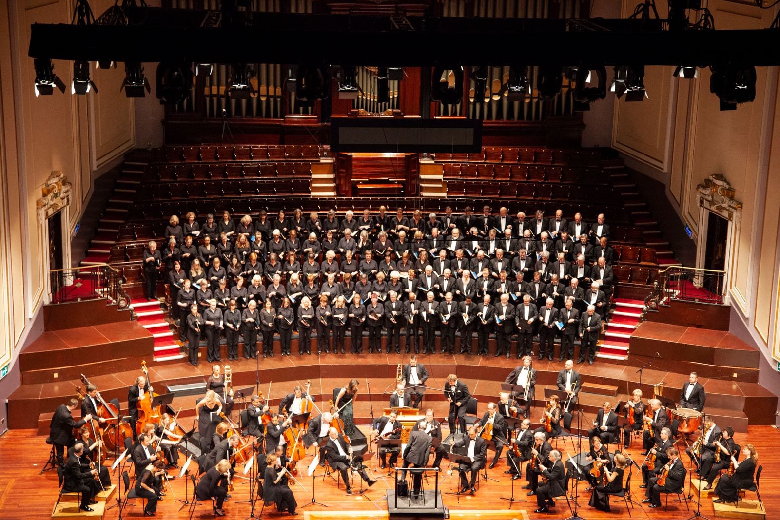 Orchestra and large choir performing in a historic concert hall